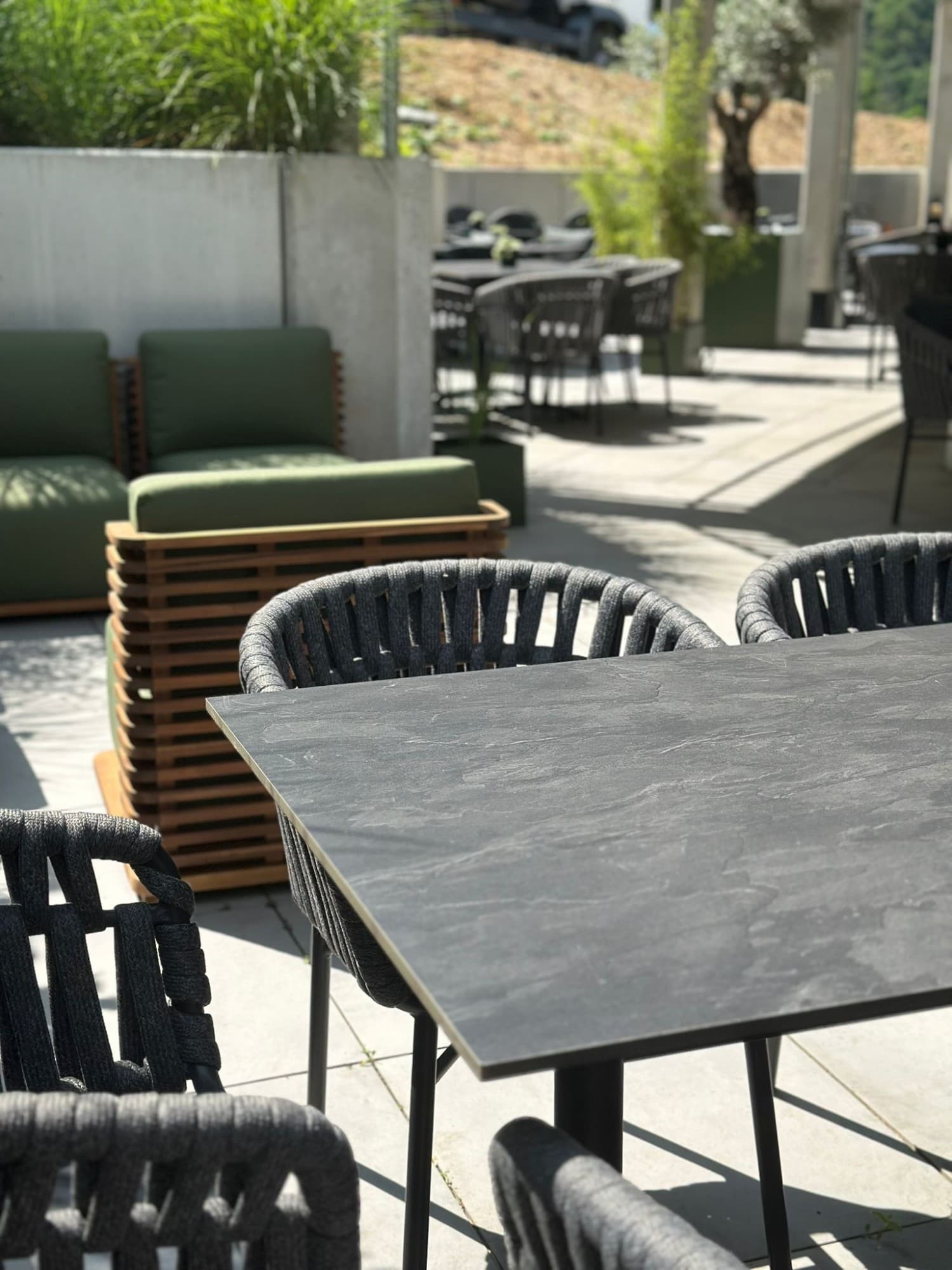 Terrasse mit gedeckten Tischen und Loungemöbeln im Grünen